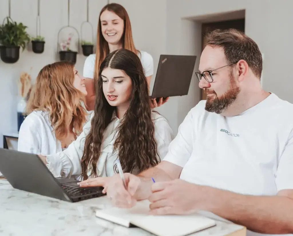 SEOCATION Team unterhält sich und schreibt auf einem Notizbuch mit